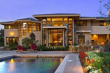 A large house with a pool and patio furniture.