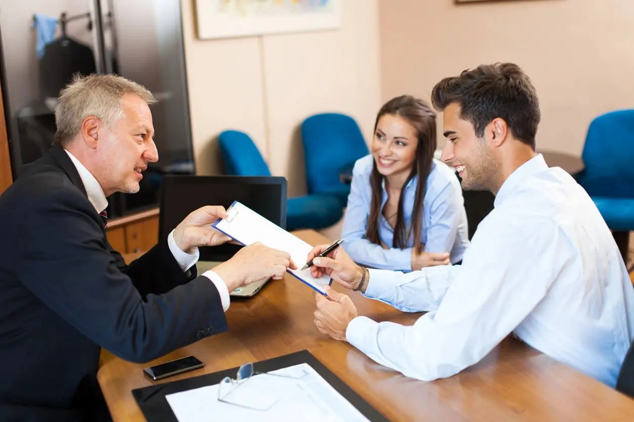 A man handing over paperwork to two people.